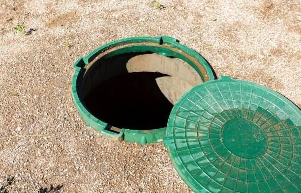 Green septic tank lid and opening in sandy soil